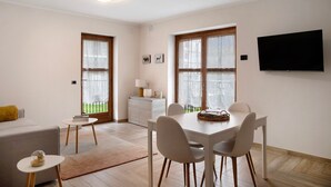 Un salon moderne comprenant un coin repas, de grandes fenêtres, un téléviseur à écran plat et un canapé.