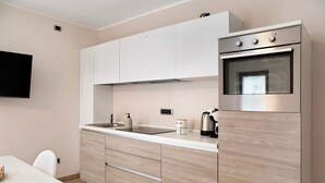 Une cuisine moderne avec des meubles blancs, un four encastré, un évier et une machine à café.