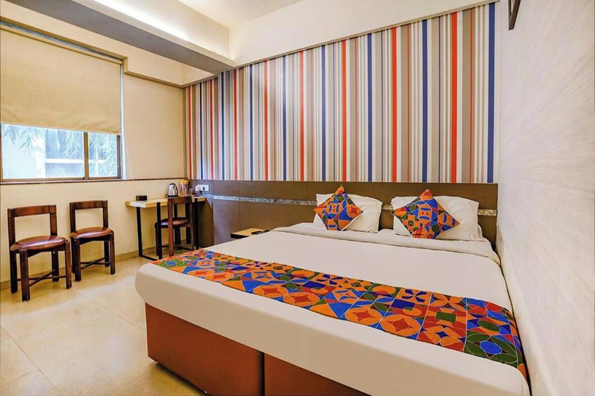A hotel room with a large bed, a desk, two chairs, and a window.