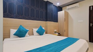 A hotel room with a large bed, two blue pillows, a white bedspread, and a blue throw. - Botanica Luxury Living Space, Gachibowli, Hyderabad (Hyderabad)