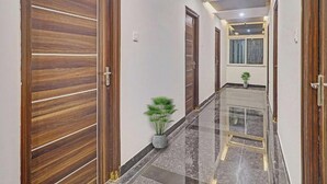 A hallway with wooden doors, a potted plant, and a tiled floor. - Botanica Luxury Living Space, Gachibowli, Hyderabad (Hyderabad)