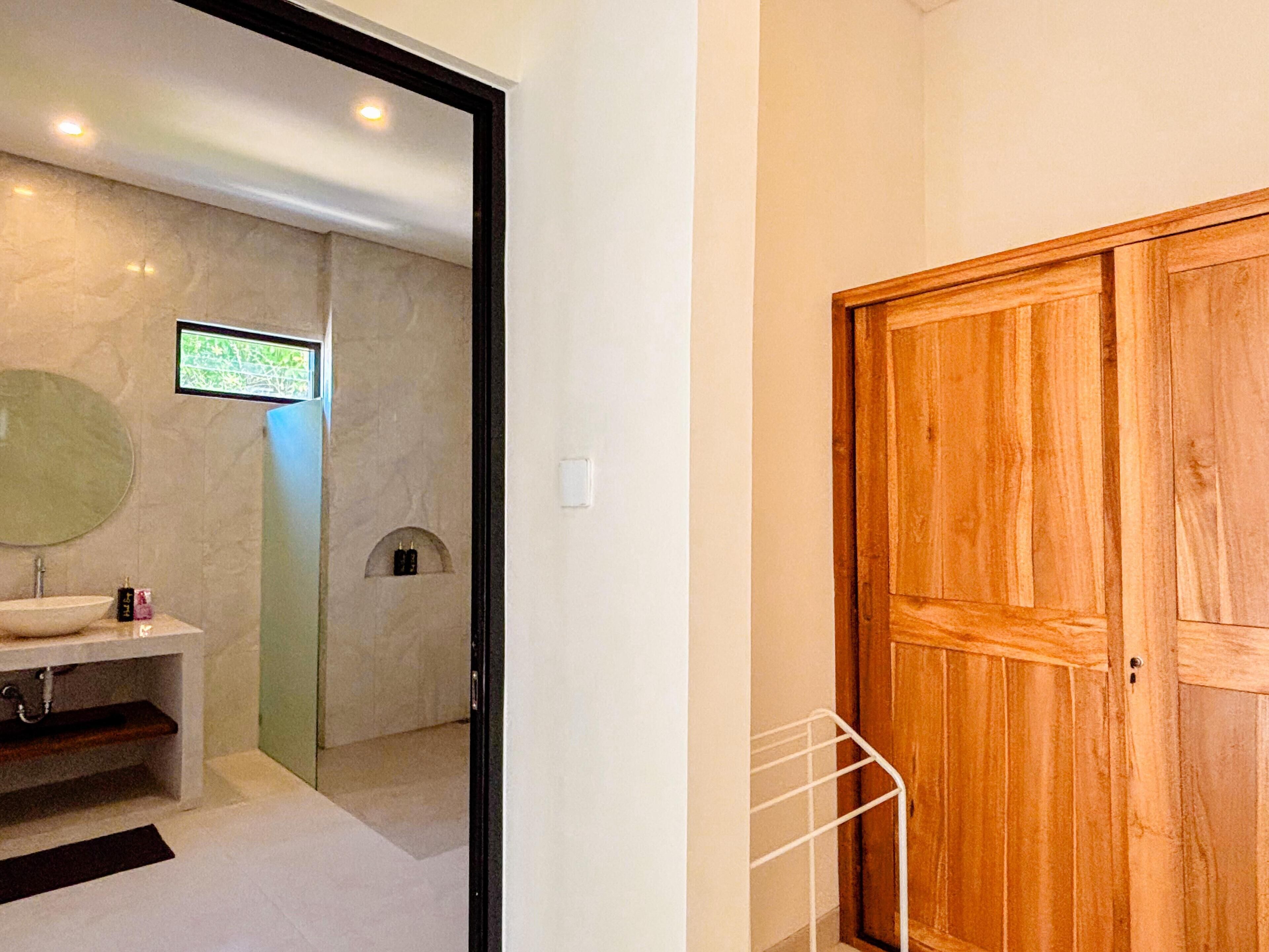 A bathroom with a sink, mirror, and shower.