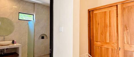 A bathroom with a sink, mirror, and shower.