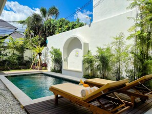 A pool area with lounge chairs, a small pool, and lush greenery. - Villa Andra Canggu (Canggu)