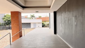 A covered walkway with a brick pillar, metal railing, and a grey wall. - Griya Dasana Residence (Curug)