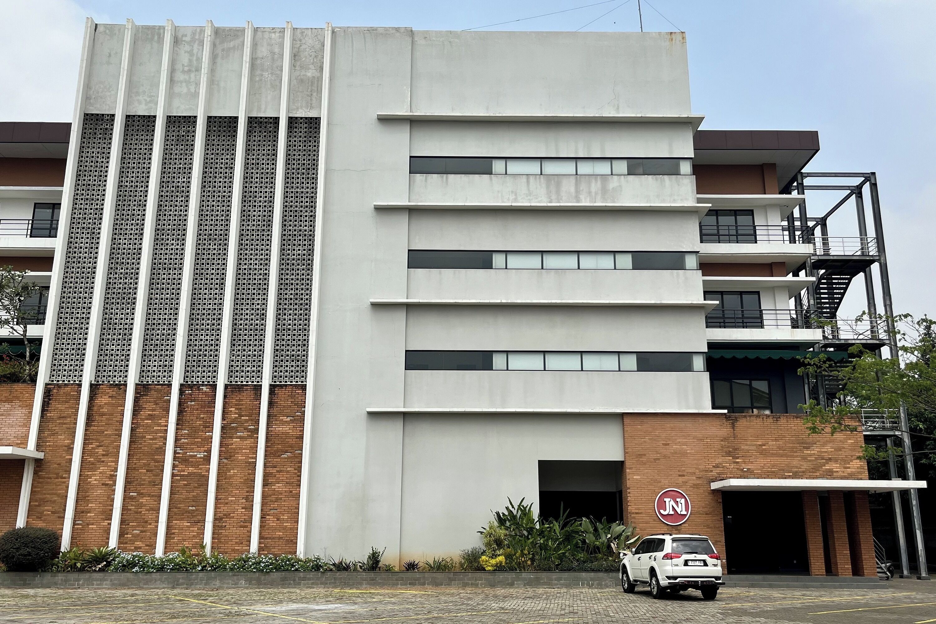 A modern building with a prominent vertical panel design, a brick facade, and a visible entrance with a sign.
