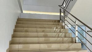 A staircase with beige steps and a metal handrail, leading to a room with a toilet sign. - Griya Dasana Residence (Curug)