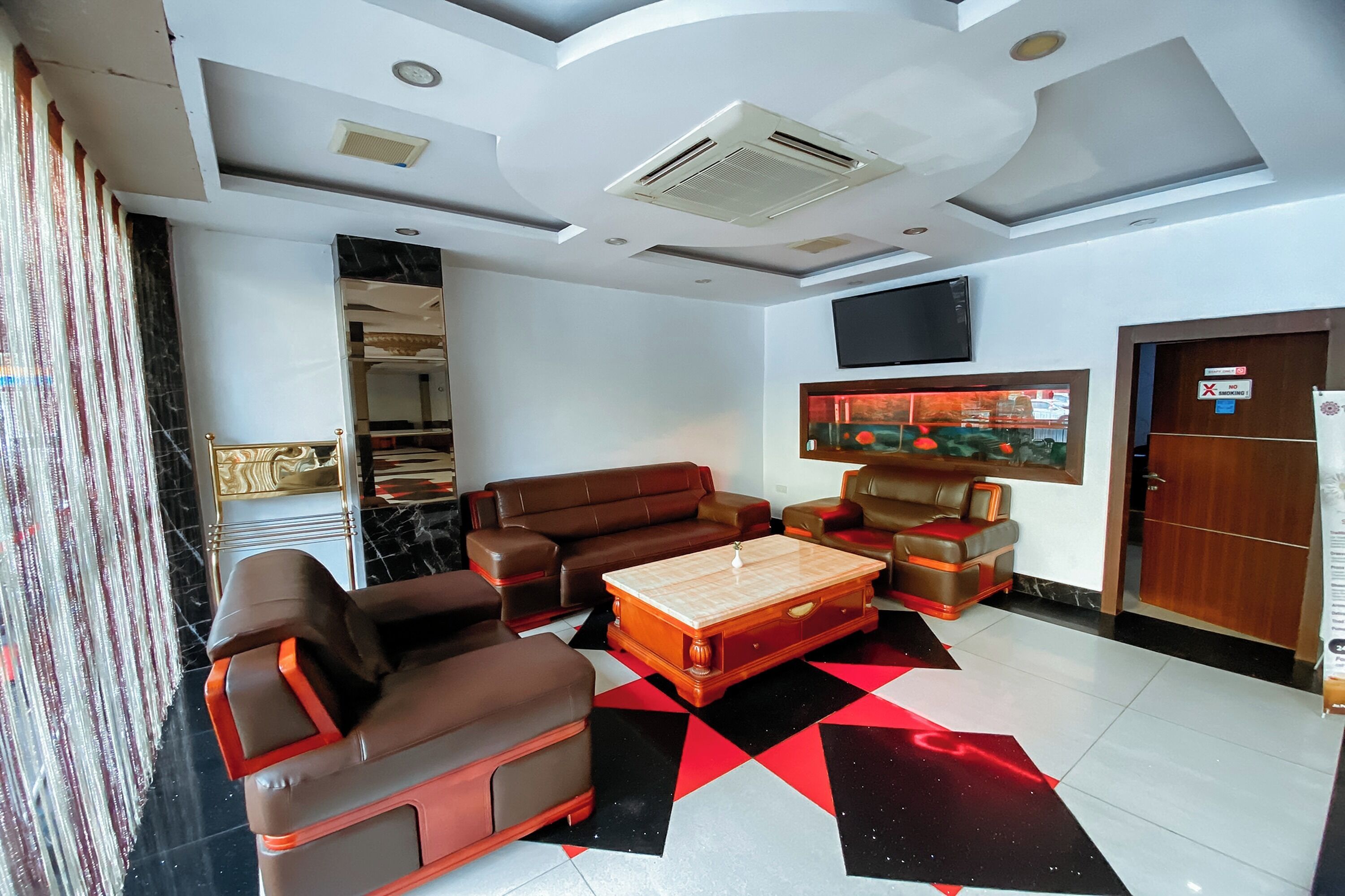 A modern living room with a brown sofa set, a wooden coffee table, and a red and black patterned rug.