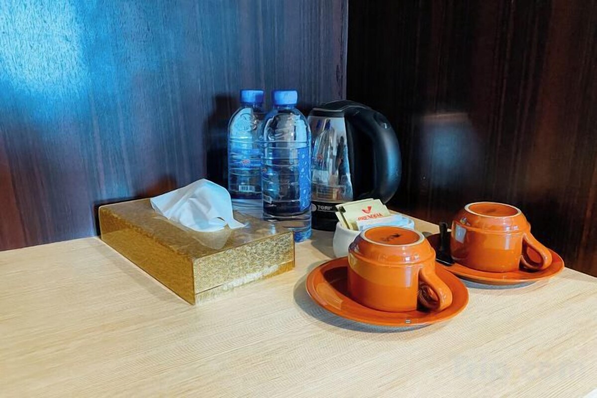 Een tafel met een zakdoos, twee waterflesjes, een koffiezetapparaat en twee oranje bekers.