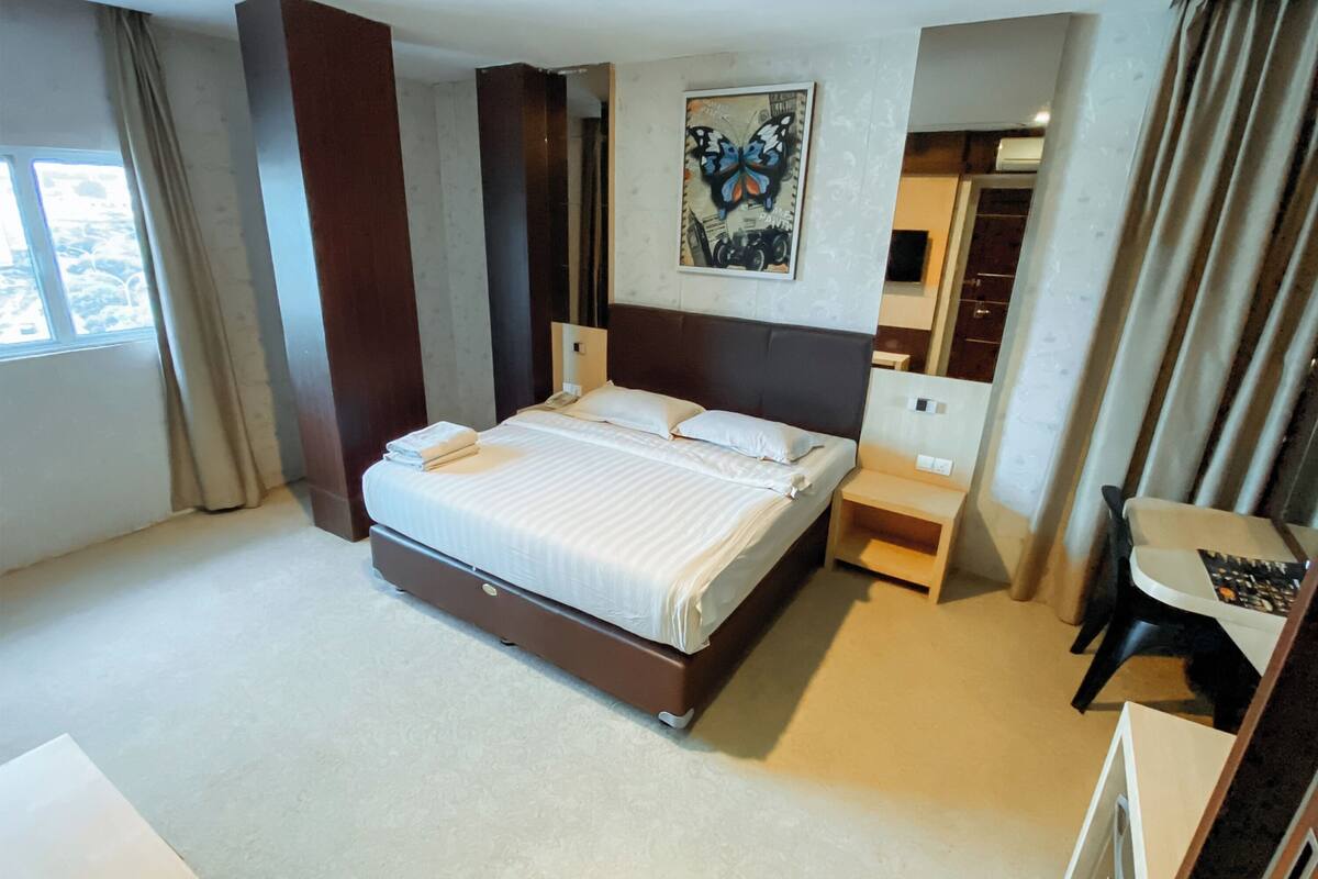 Una habitación de hotel con una cama grande, mesitas de noche, un escritorio, una silla y un armario.