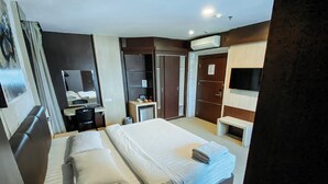 A hotel room with a large bed, a desk, a wardrobe, and a TV. - Lucky Star Hotel Near Harbour Bay Batam (Batam)
