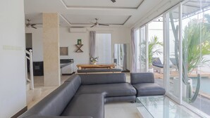 Un salon moderne avec un canapé d’angle, une table basse en verre et une vue sur une piscine.