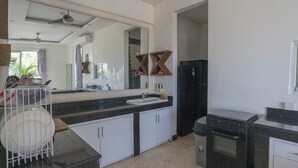 Une cuisine moderne avec un plan de travail noir, des placards blancs, un évier, une cuisinière et un miroir.