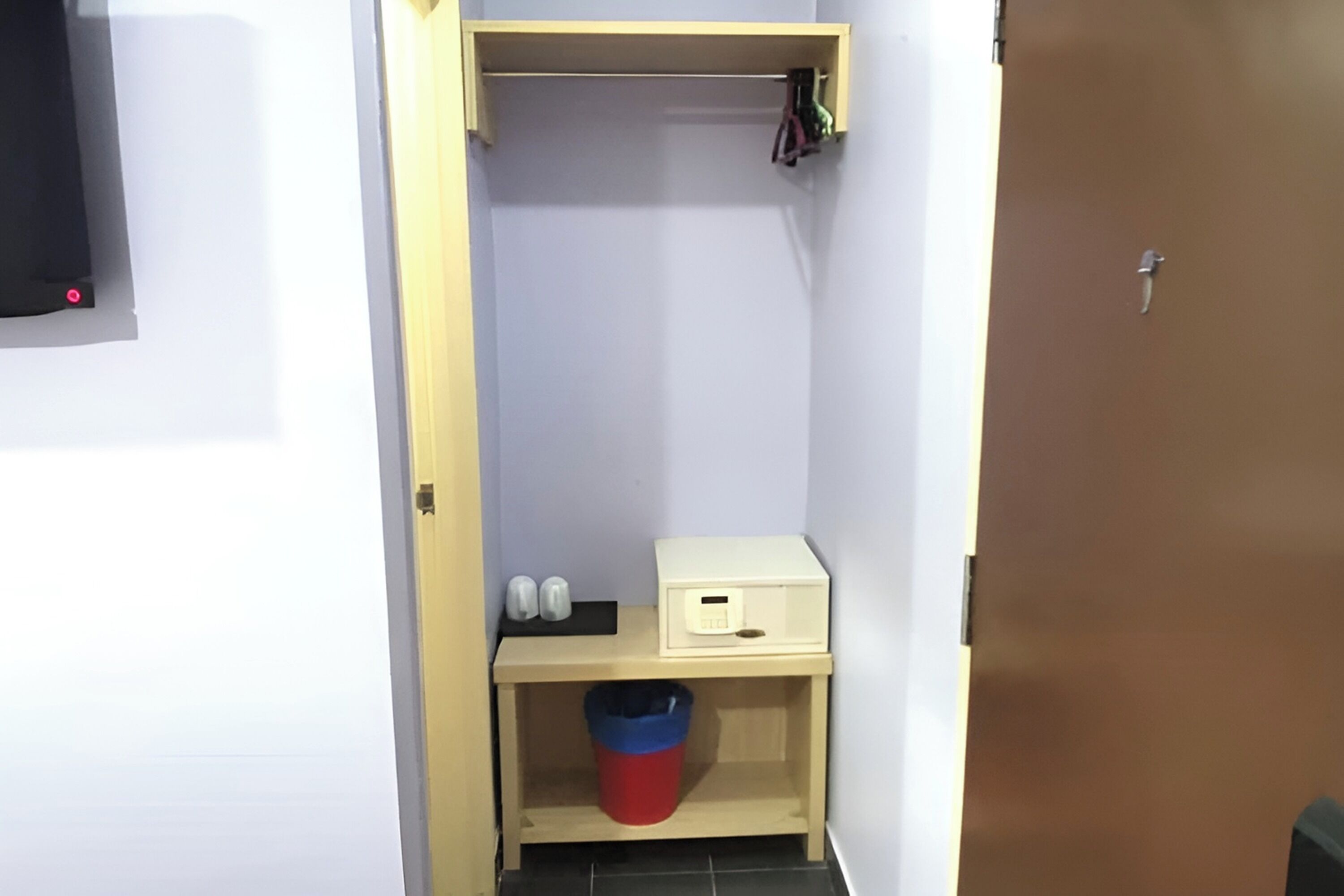 A small room with a wooden shelf, a trash bin, and a white box.