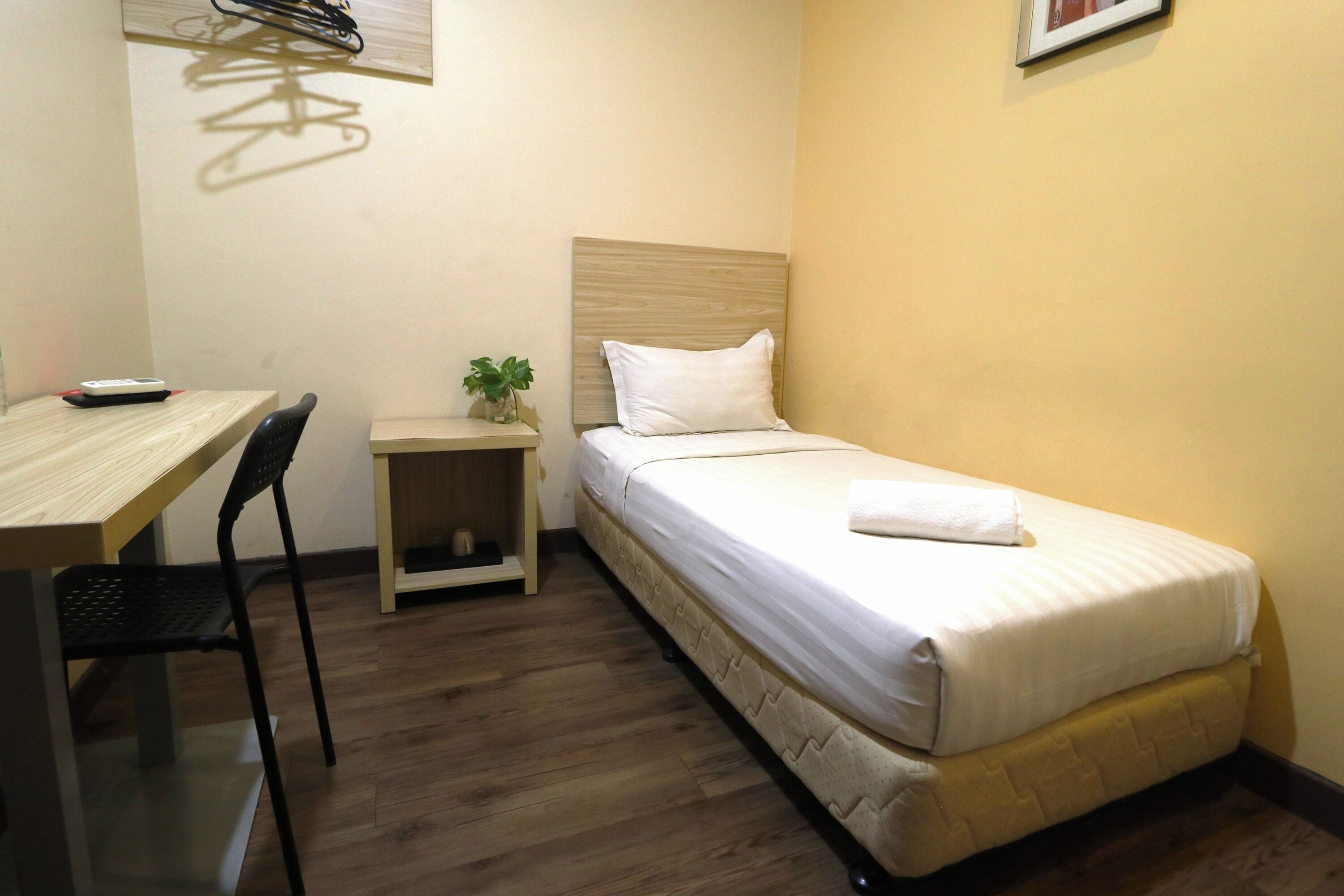 Une petite chambre à coucher, bien rangée, avec un lit simple, une table de chevet, une chaise et un bureau.