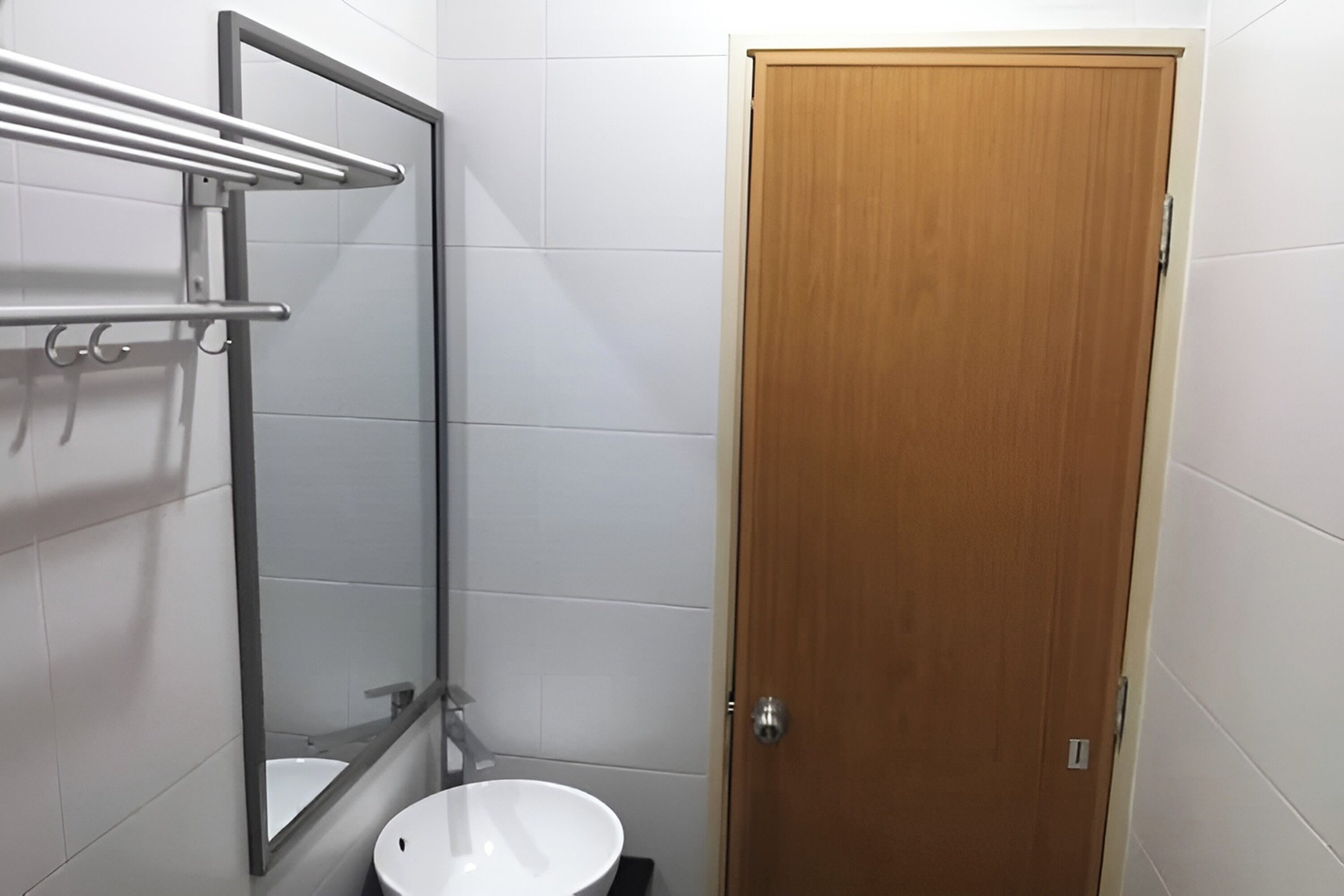 A bathroom with a wooden door, a white sink, and a mirror with a metal frame.