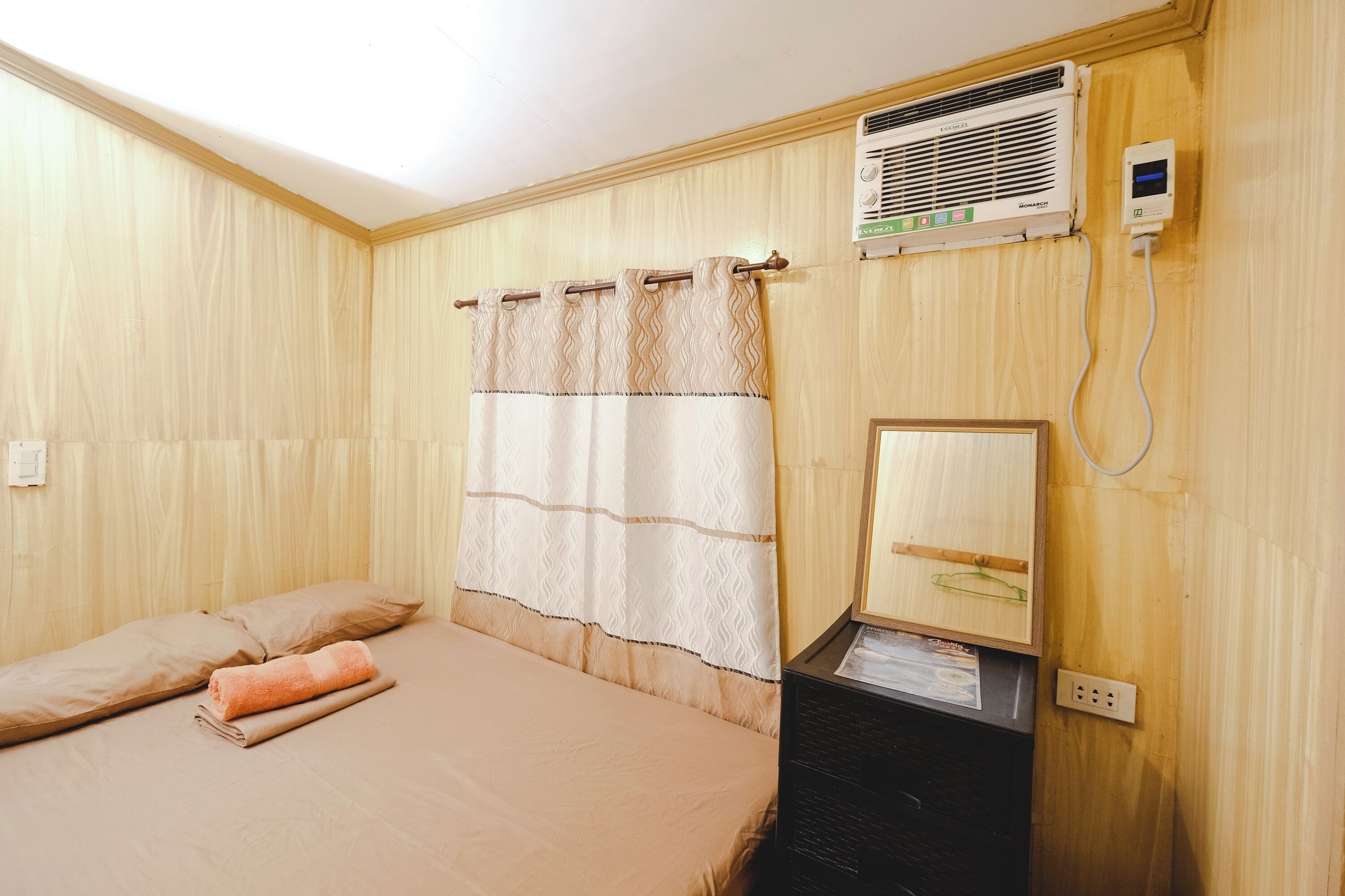 Un dormitorio con cama, aire acondicionado de pared y un espejo.