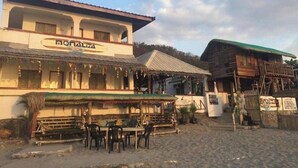 A building with a sign reading "nonaliza" and a covered outdoor seating area with tables and chairs. - Monaliza Surf Resort (San Juan)