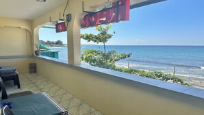 A balcony with a view of the sea, a table, chairs, and a potted plant. - Monaliza Surf Resort (San Juan)