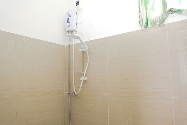 Eine Dusche mit Duschbrause und verstellbarer Armatur an der Wand.