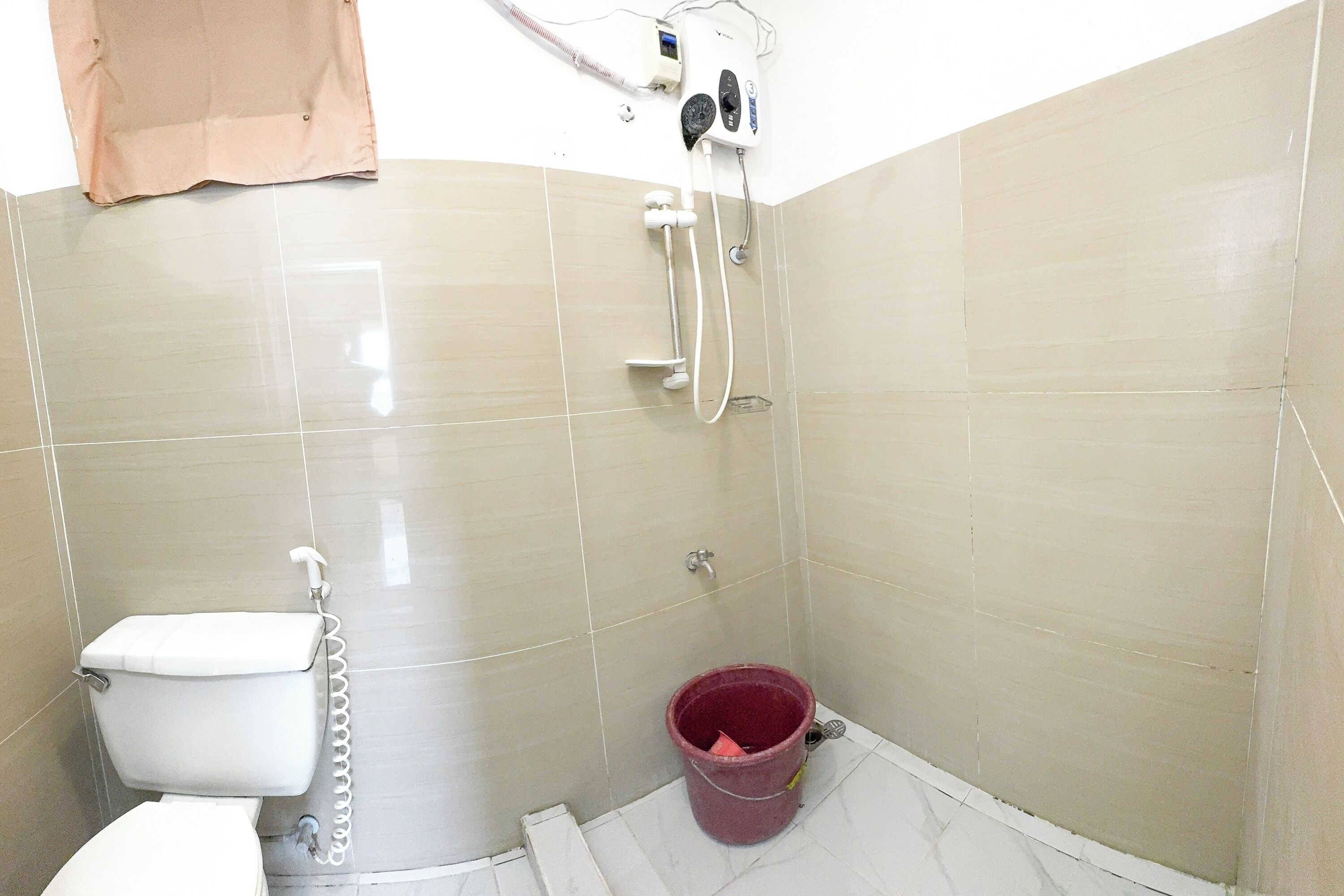 Un baño pequeño con inodoro, ducha y un balde.