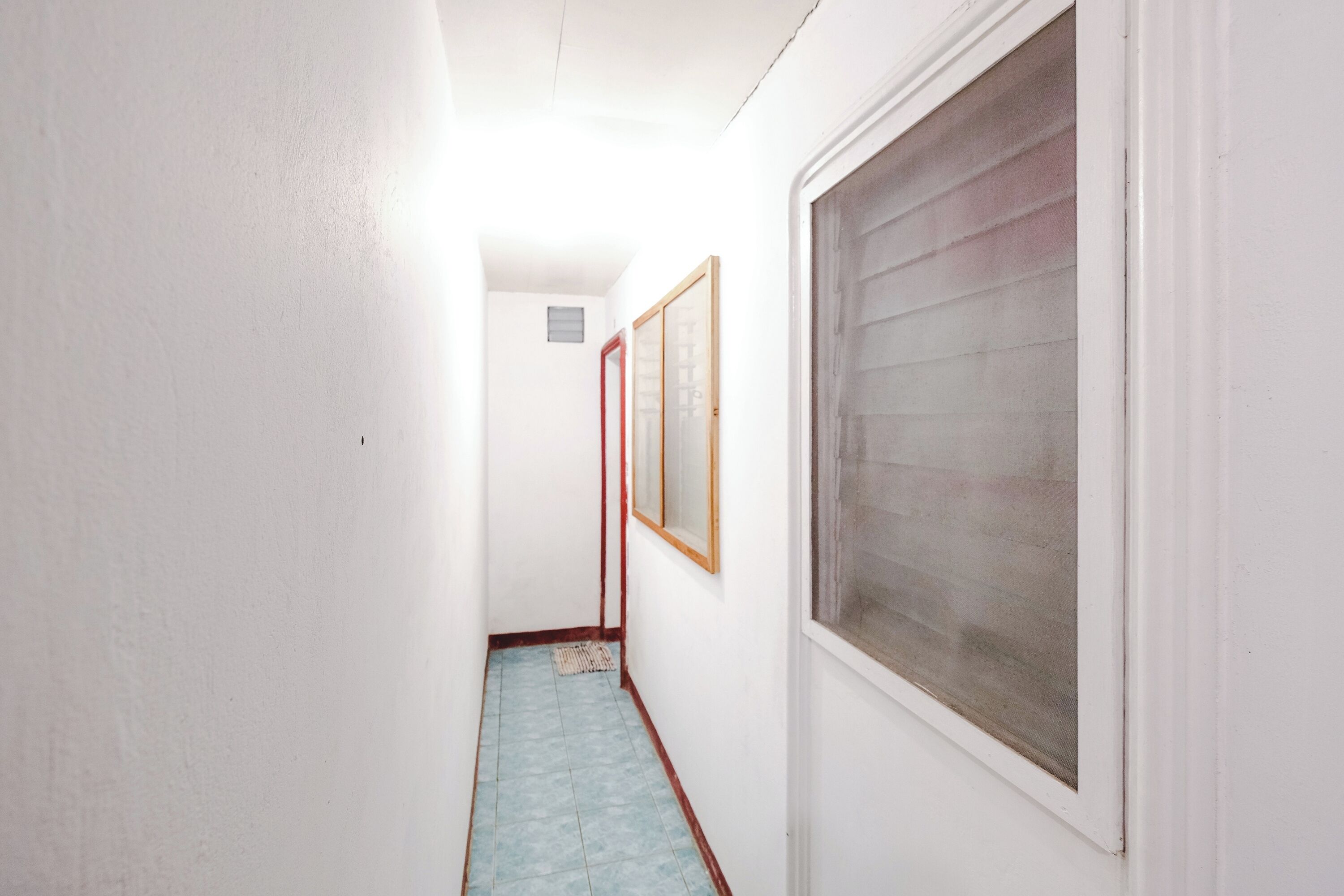 A narrow hallway with a window on the right and a door at the end.