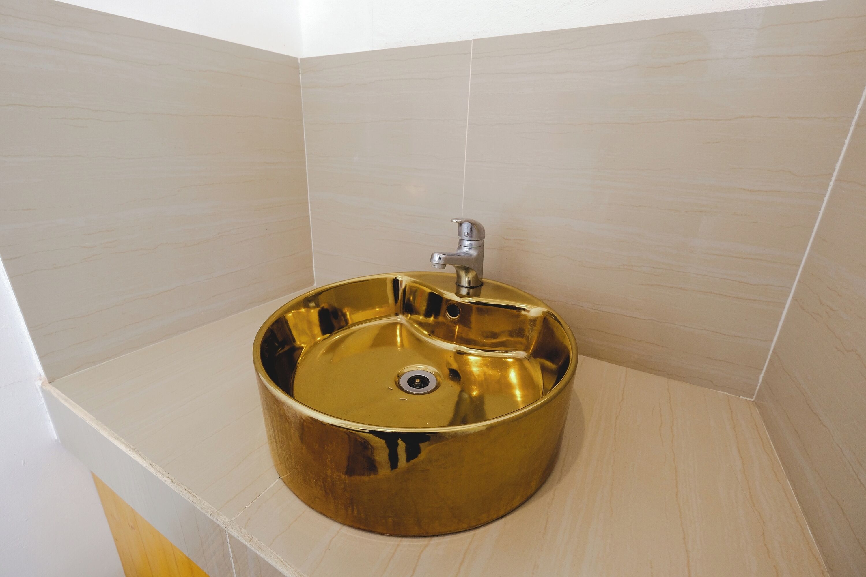 A bathroom with a gold sink and white tiles.