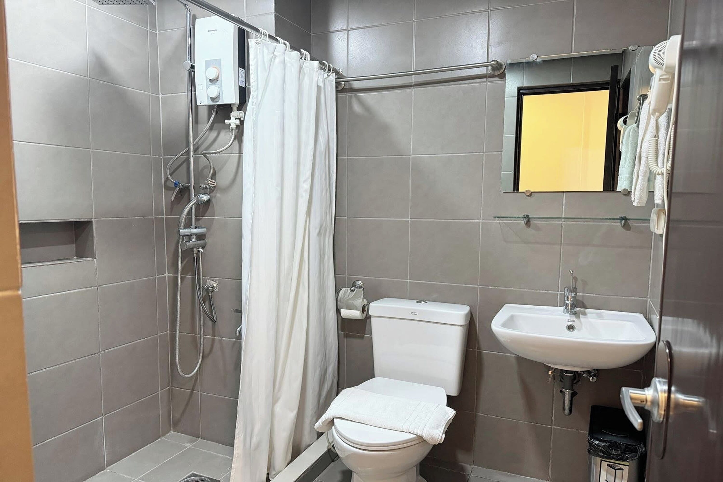 Un baño con ducha, inodoro, lavabo y espejo con marco amarillo.