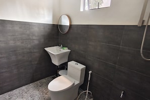 A bathroom with a toilet, sink, and mirror. - Casa Calungsod La Union (San Juan)