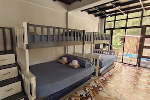 A room with bunk beds, a small desk, and a window with a view of the outside. - Casa Calungsod La Union (San Juan)