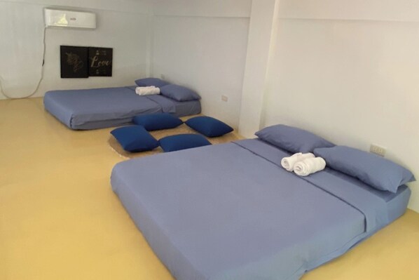 A room with two beds, each with blue bedding and pillows. There are towels on one bed. - Casa Calungsod La Union (San Juan)