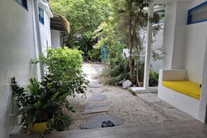 A narrow pathway with stepping stones leading to a white building with a yellow bench. - Deva Casa Private Pool Villa (Pattaya)