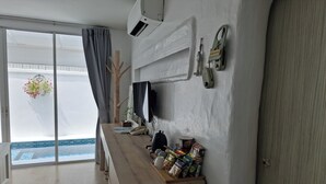 Une chambre d’hôtel avec un bureau en bois, un téléviseur à écran plat, un téléphone et une fenêtre donnant sur une piscine.