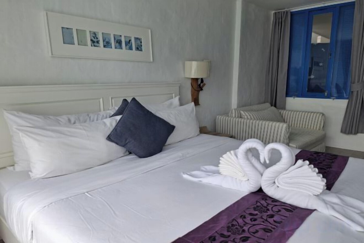 A hotel room with a bed, a bedside lamp, a window with curtains, and a wall-mounted picture.