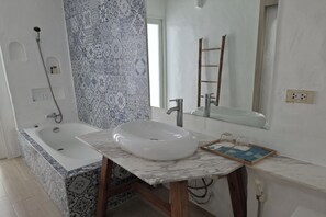 A bathroom with a bathtub, a white sink, and a mirror. - Deva Casa Private Pool Villa (Pattaya)