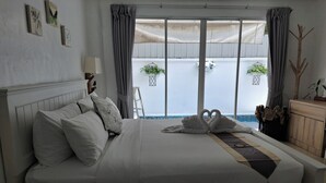 Une chambre d’hôtel avec un grand lit, une vue sur le balcon extérieur et une petite table avec une lampe.