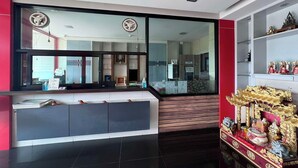 A reception area with a modern design, featuring a large glass window, a reception desk, and a decorative altar with religious statues. - The Nine Place (Hat Yai)