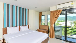 A hotel room with a large bed, a chair, a balcony with a view, and an air conditioning unit. - The Nine Place (Hat Yai)