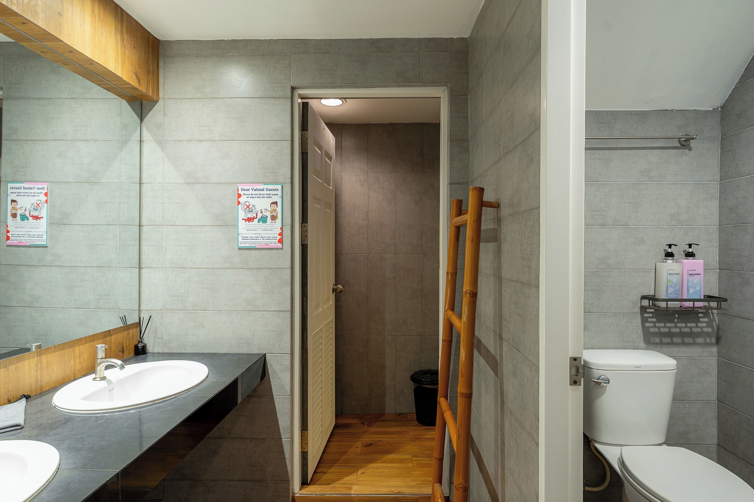A bathroom with a wooden door, a white sink, a mirror, and a toilet.
