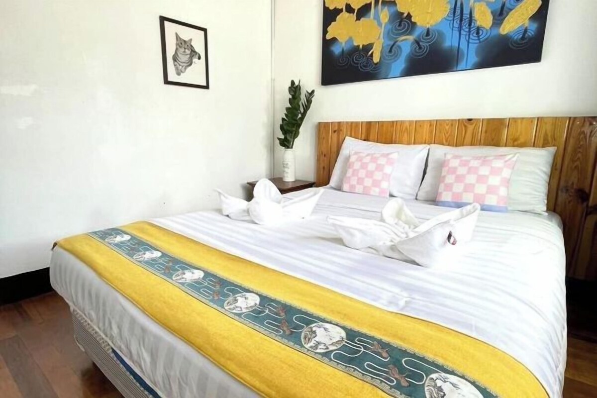 Una cama bien hecha con un cojín a cuadros, un cojín decorativo y una manta estampada.