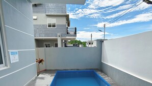 A swimming pool with a blue tiled interior, surrounded by a grey wall and a white fence. - Ada's Residential Villa La Union (Bacnotan)