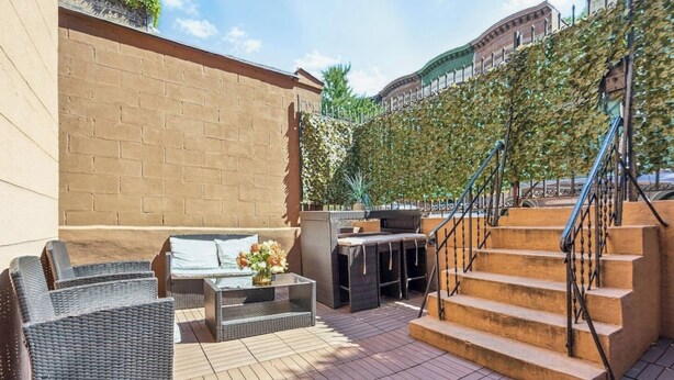Un patio al aire libre con mobiliario de mimbre, un sofá y una escalera.