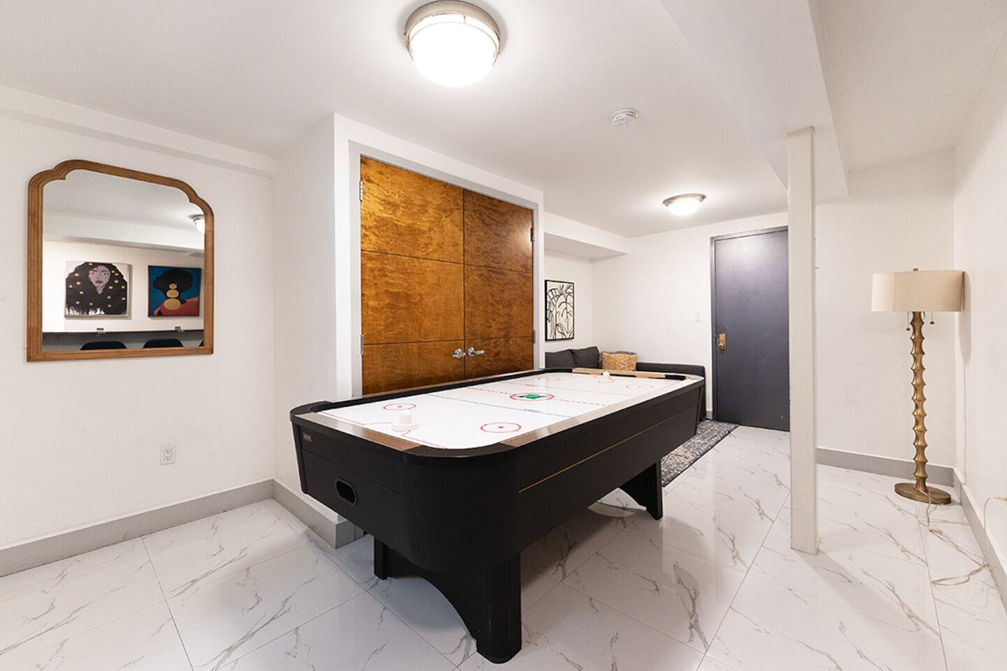 A spacious room with a pool table, a large mirror, and a wooden cabinet.