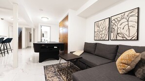 Una sala de estar moderna con mesa de billar, un sofá y dos cuadros en la pared.