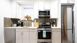 Una cocina moderna con electrodomésticos de acero inoxidable, estufa a gas, microondas y refrigerador.