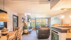 A cozy living area with a wooden dining table, leather sofa, and a kitchen island. - Mountain Plaza 310  1 BD/ 2 BA (Copper Mountain)