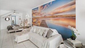 Una sala de estar moderna con un mural grande, un sofá, una mesa de centro y una estantería.