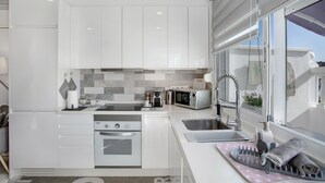 Una cocina moderna con armarios blancos, horno empotrado, microondas y ventana con vistas.