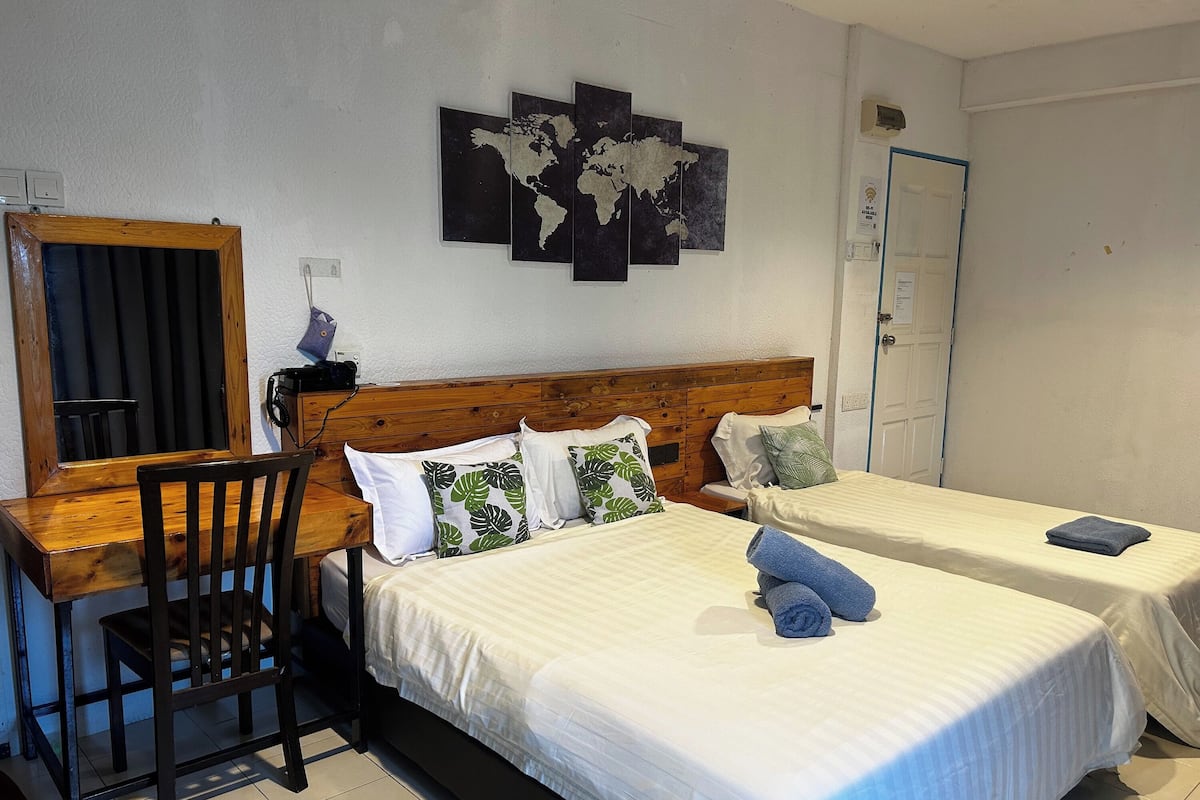 A room with two beds, a wooden desk, a chair, and a world map on the wall.