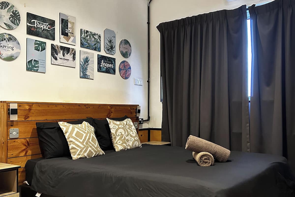 A bedroom with a wooden headboard, a black bedspread, and decorative wall art.